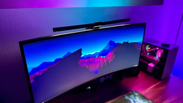 Quntis RGB Pro on an ultrawide monitor next to a gaming desktop PC.