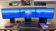 Uplift V2 Commercial Standing Desk image with three monitors, laptop, desktop, Steam Deck, XBox controller, keyboard, mouse and iPad.